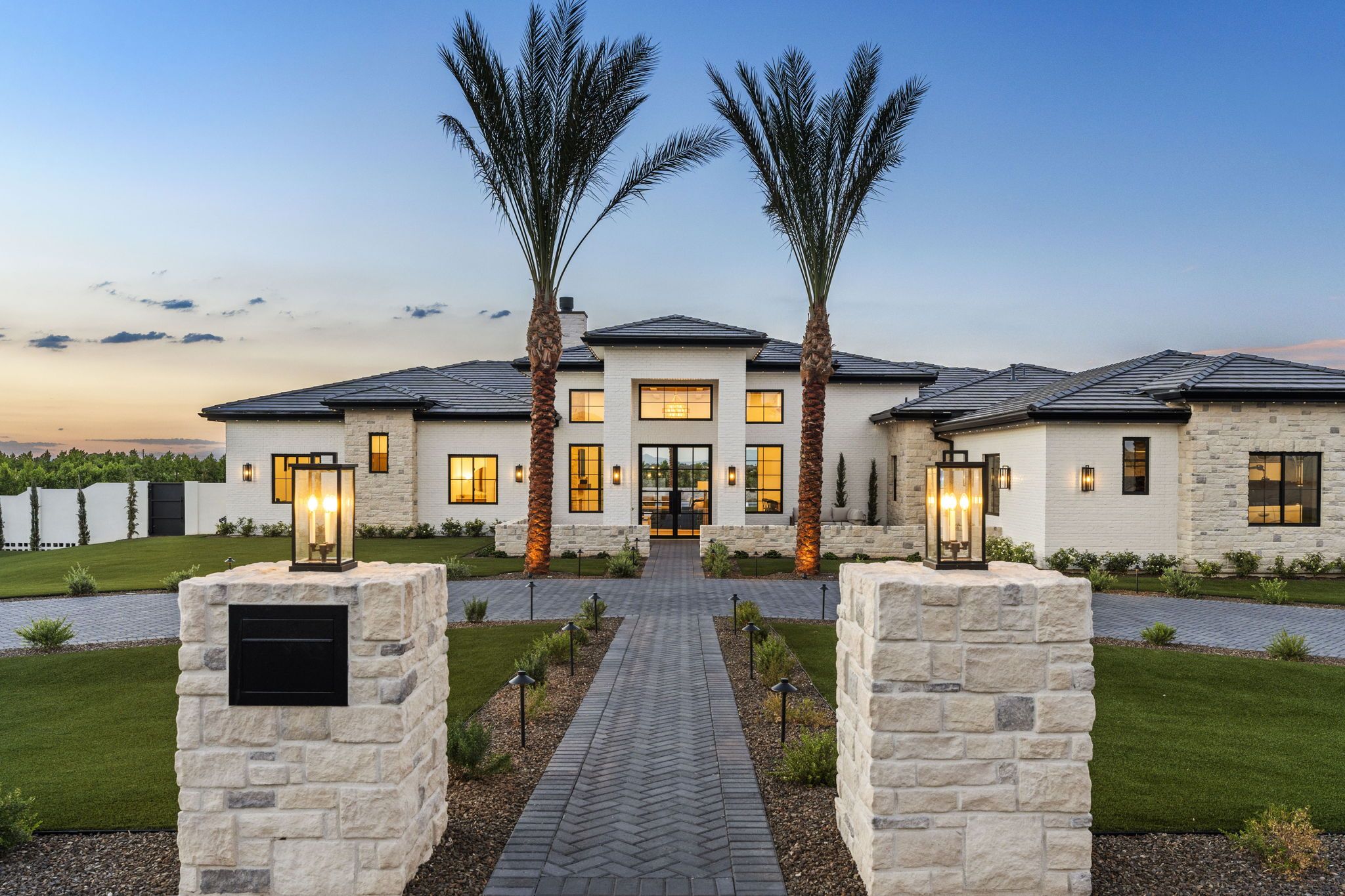 Twilight view of the stone entry pillars and lighted walkway at 21712 E Pegasus Pkwy, Queen Creek AZ