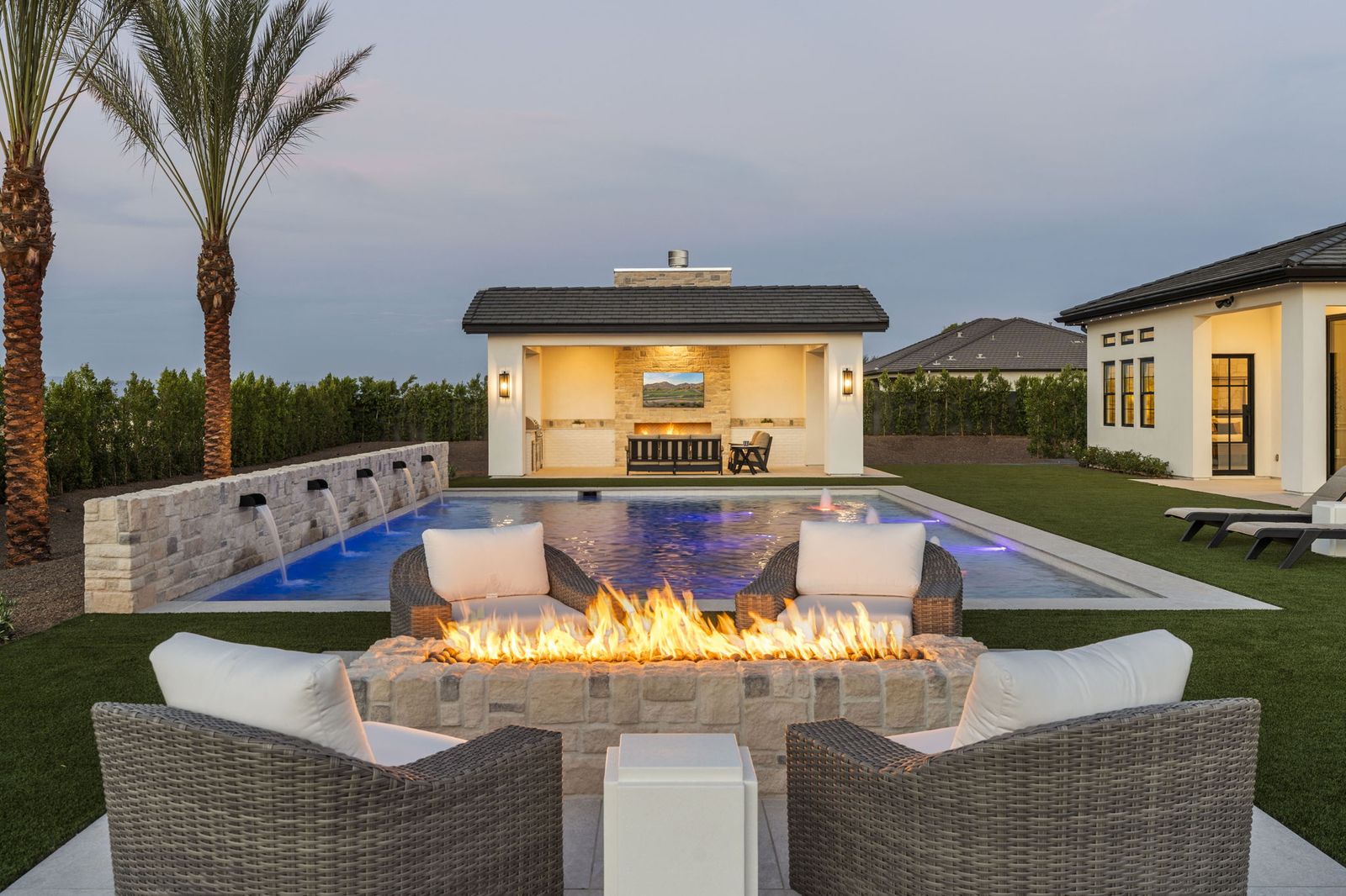 Gas fire pit at twilight beside the pool at a Prestige Build Co. custom home